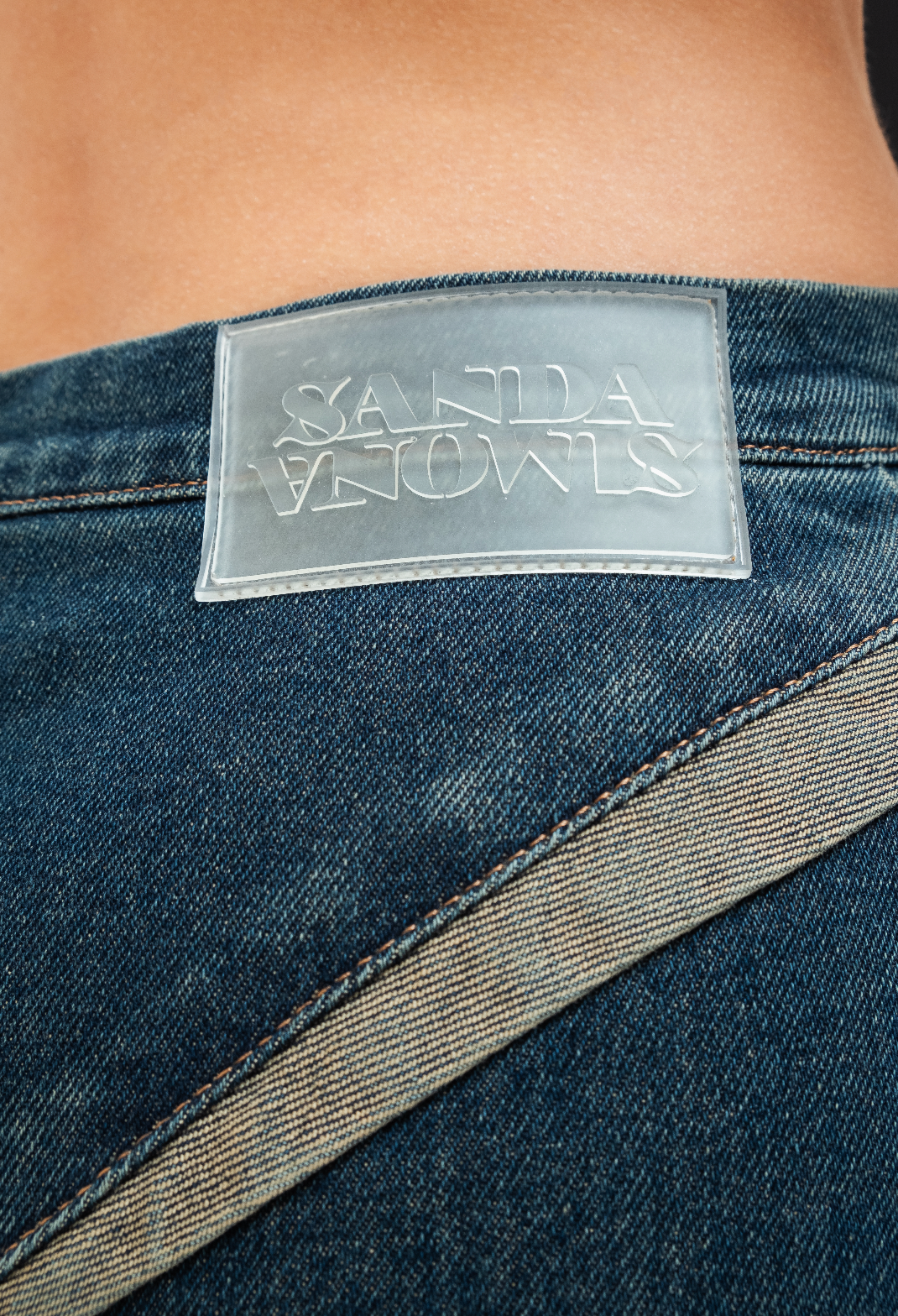 Close up view of the logo sandasimona on denim dark blue jeans.